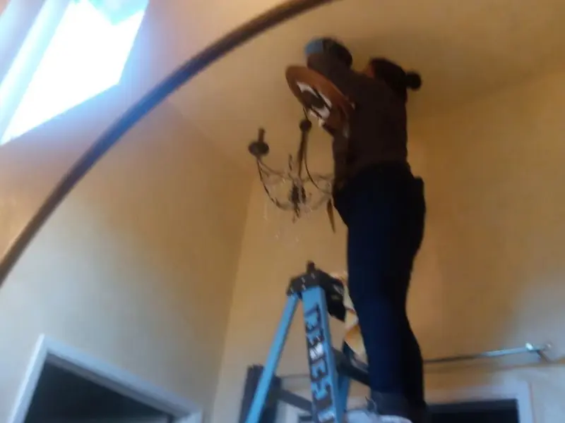 Electrician installing a chandelier in a Hattiesburg residence